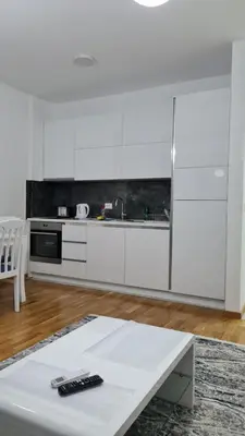 a white kitchen with white cabinets and a table at Apartman A1 in Ulcinj