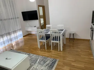 a living room with a table and chairs and a television at Apartman A1 in Ulcinj