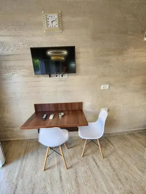 a table and two chairs with a television on a wall at Ebra Lux Apartmani in Dobra Voda