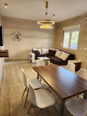 a living room with a wooden table and white chairs at Ebra Lux Apartmani in Dobra Voda