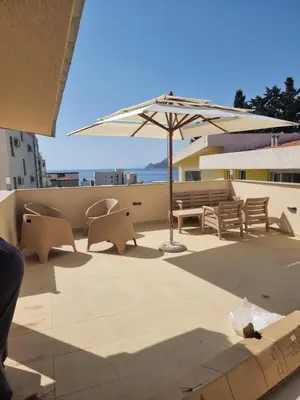 a patio with a table and an umbrella and benches at Ebra Lux Apartmani in Dobra Voda