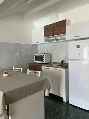 a kitchen with a table and a white refrigerator at GRAMISI apartments in Kruče