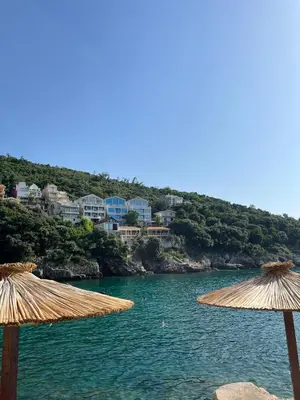 two straw umbrellas sitting on a beach in the water at GRAMISI apartments in Kruče