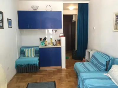 a living room with two blue couches and a kitchen at Bolux Studio Apartment in Budva