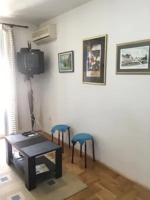 a living room with a table and two blue stools at Bolux Studio Apartment in Budva