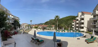 a swimming pool with chairs and umbrellas in a resort at Sunset Poolside Retreat BlueH in Budva