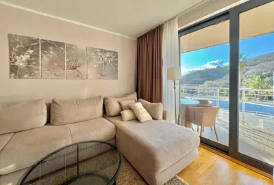 a living room with a couch and a balcony at Sunset Poolside Retreat BlueH in Budva