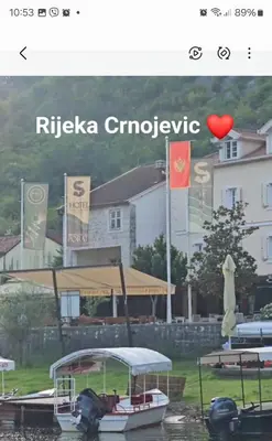 a boat in the water in front of a house at Hotel S Family Jovicevic in Rijeka Crnojevića