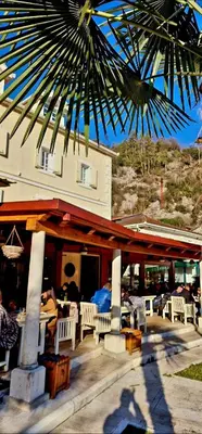 a restaurant with tables and chairs and a palm tree at Hotel S Family Jovicevic in Rijeka Crnojevića