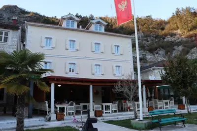 a building with a flag in front of it at Hotel S Family Jovicevic in Rijeka Crnojevića