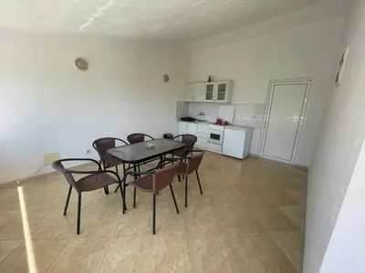a dining room with a table and chairs and a kitchen at Vila Goga in Ulcinj