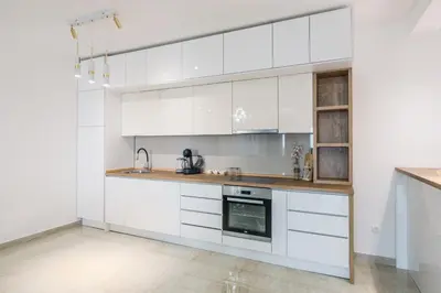 a white kitchen with white cabinets and an oven at Vila katune 2022 in Ulcinj