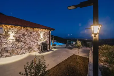 a house with a stone wall and a street light at Vila katune 2022 in Ulcinj