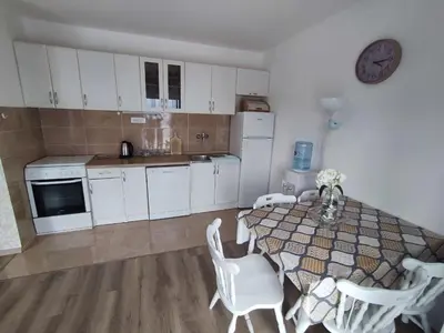 a kitchen with a table and white cabinets and white appliances at Apartmani Bellami in Becici