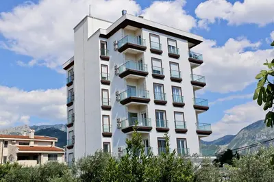 a white building with balconies and mountains in the background at Luxury Mare apartment in Bar