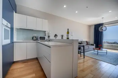 a kitchen with white cabinets and a living room at City Apartments 2 in Budva