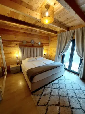 a bedroom with a large bed in a wooden room at Villa Butterfly Valdanos in Ulcinj