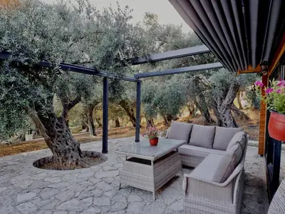 a patio with a couch and a table and trees at Villa Butterfly Valdanos in Ulcinj