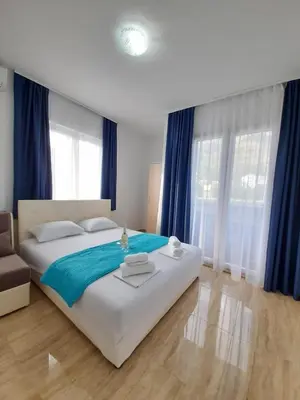 a bedroom with a large bed with blue curtains at Black & White in Sutomore