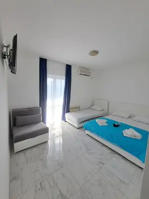 a white room with two beds and a chair at Black & White in Sutomore