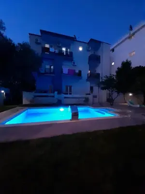 a swimming pool in front of a building at night at Black & White in Sutomore