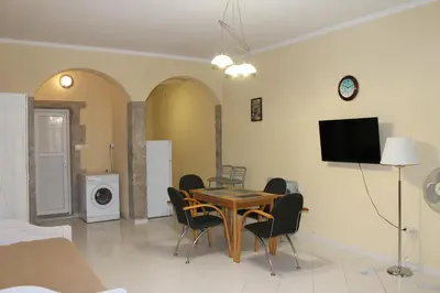 a dining room with a table and chairs and a tv at Апартаменты Jasmine in Bar
