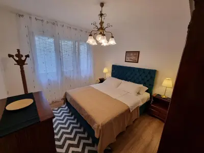 a bedroom with a large bed and a chandelier at Golden Fields Apartment near the Old Town in Kotor