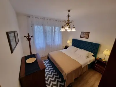 a bedroom with a bed with a blue headboard and a table at Golden Fields Apartment near the Old Town in Kotor