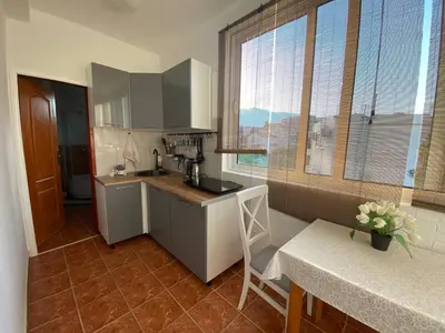 a kitchen with a counter and a table and some windows at Alina's apartment in Becici