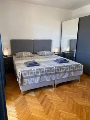 a bedroom with a large bed and a wooden floor at Alina's apartment in Becici