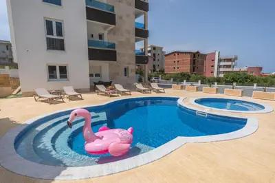 a swimming pool with a pink flamingo in the water at Zodea Apartments in Dobra Voda