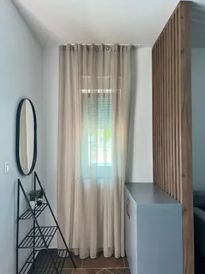a living room with a curtain and a mirror at Zodea Apartments in Dobra Voda