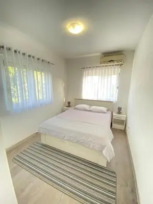 a bedroom with a white bed and a large rug at Home Mia Airport in Podgorica