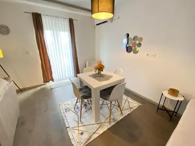 a dining room with a white table and chairs at Home Mia Airport in Podgorica