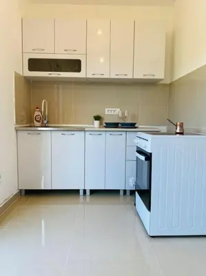 a kitchen with white cabinets and a stove top oven at Home Mia Airport in Podgorica