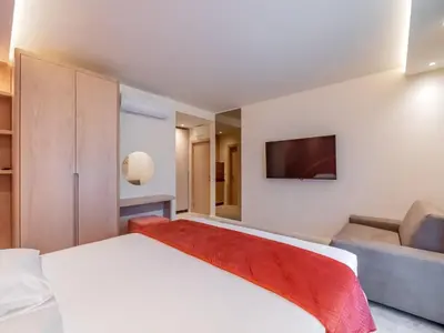 a bedroom with a white bed and a flat screen tv at Vila Gina in Bar