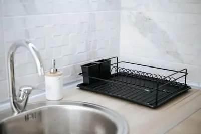 a kitchen counter with a metal drying rack next to a sink at Apartmani Vittoria in Bar