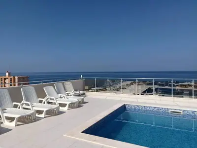 a balcony with chairs and a swimming pool and the ocean at Apartments Meri in Dobra Voda