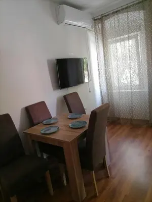 a dining room table with chairs and a television at Apartmani 15 in Cetinje