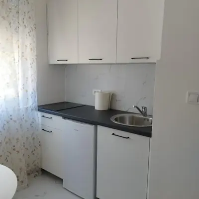 a kitchen with white cabinets and a sink at Apartmani 15 in Cetinje