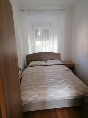 a bed in a white bedroom with a window at Apartmani 15 in Cetinje