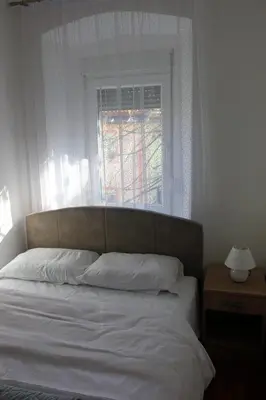 a bed with white pillows and a window in a bedroom at Apartmani 15 in Cetinje