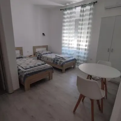 a room with two beds and a table and chairs at Apartmani 15 in Cetinje