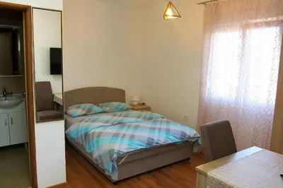 a small bedroom with a bed and a mirror at Apartmani 15 in Cetinje