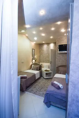 a hotel room with three beds and a tv at Apartments Lidija in Petrovac na Moru