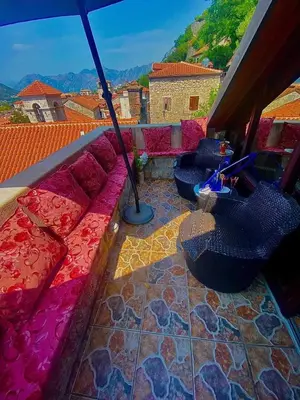 a balcony with a pink couch and an umbrella at Vincenza Apartment in Kotor