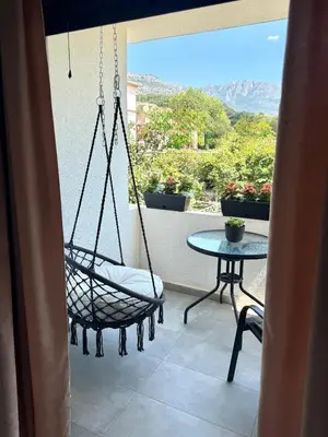 a porch with a swing and a table on a balcony at Danin apartmani in Bar