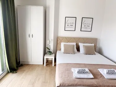 a white bedroom with two beds and a closet at Danin apartmani in Bar