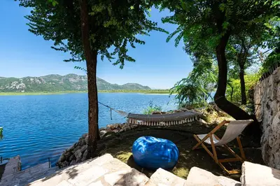 a hammock and a chair next to a lake at Villas Katarina Skadar Lake in Cetinje