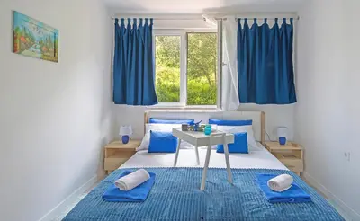a bedroom with a bed with blue pillows and a table at Harmony in Radanovići